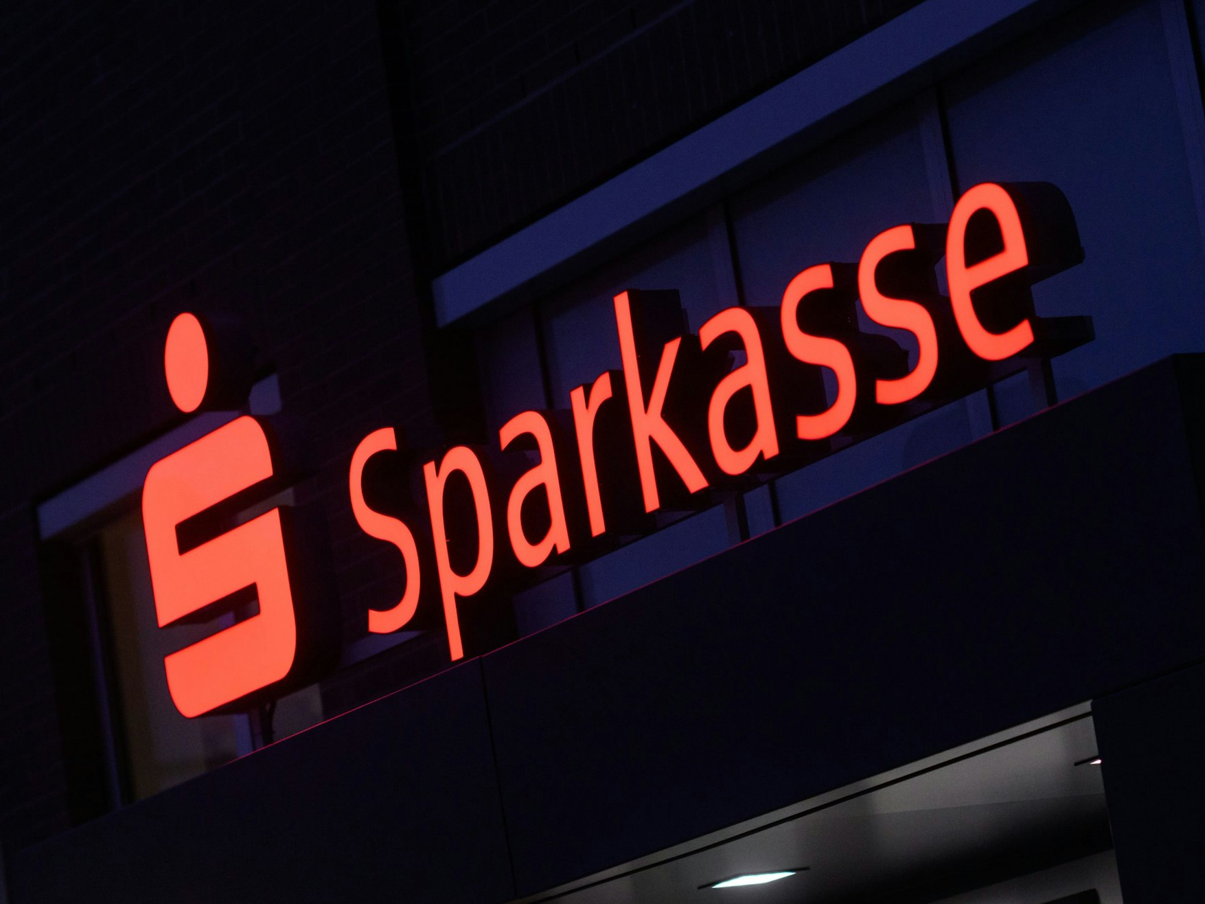 Ein Schriftzug der Sparkasse leuchtet an einer Filiale in der Region Hannover, hier im Januar 2023.