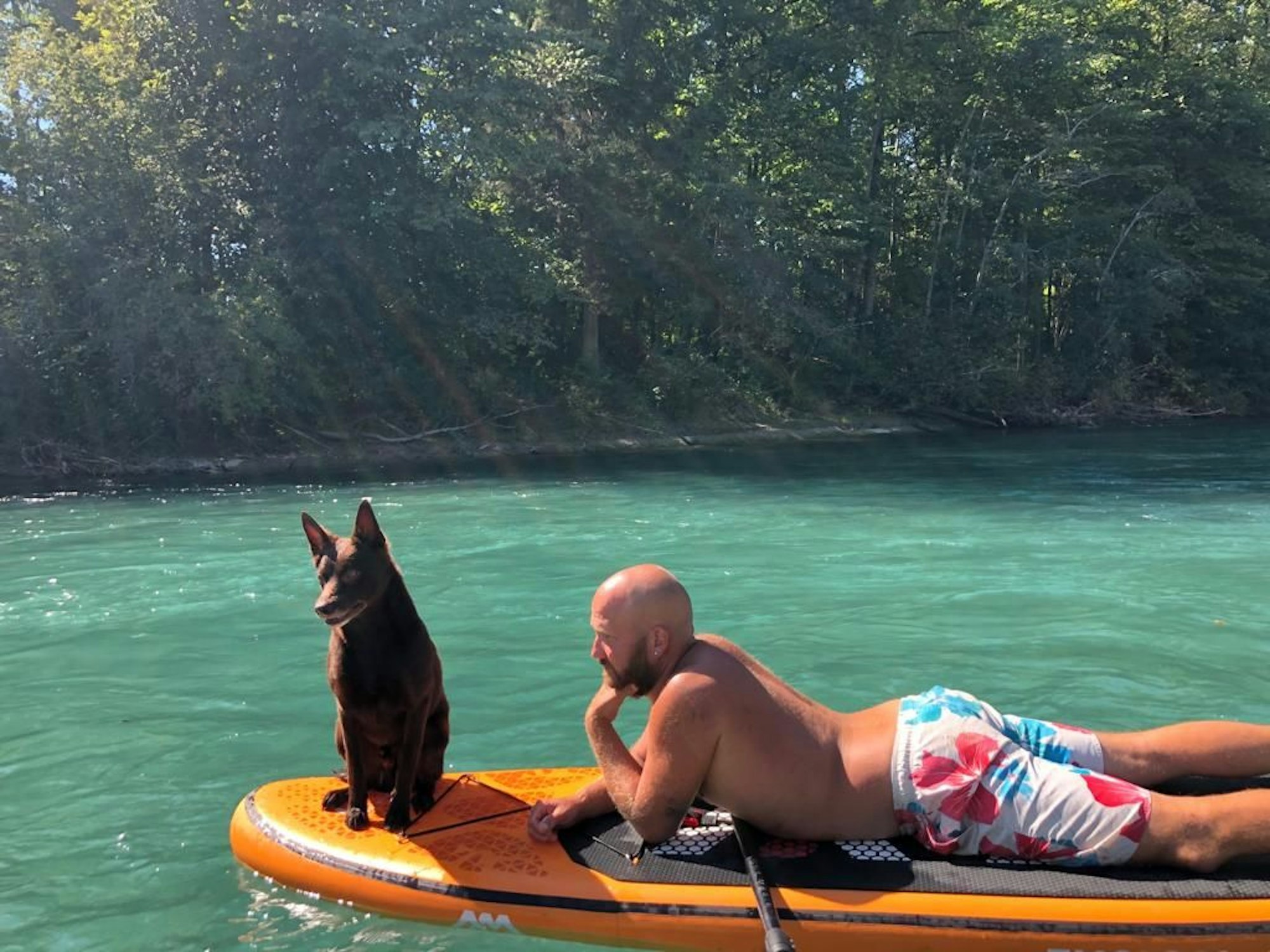 Entspannt: Coach Florian Hornig mit seinem Hund Django auf einem Surfbrett.