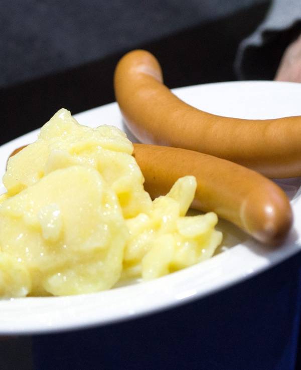 Würstchen mit Kartoffelsalat liegen auf einem Teller.