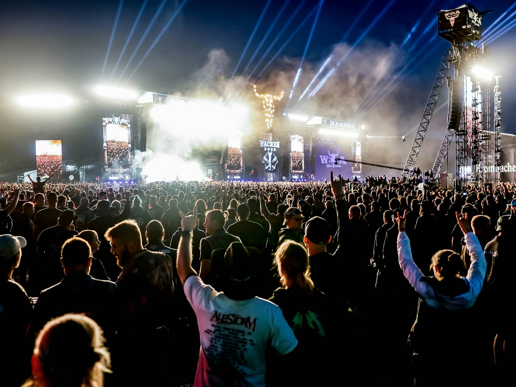 Festival-Besucher und Besucherinnen feiern auf dem Wacken-Veranstaltungsgelände vor den Haupt-Bühnen.