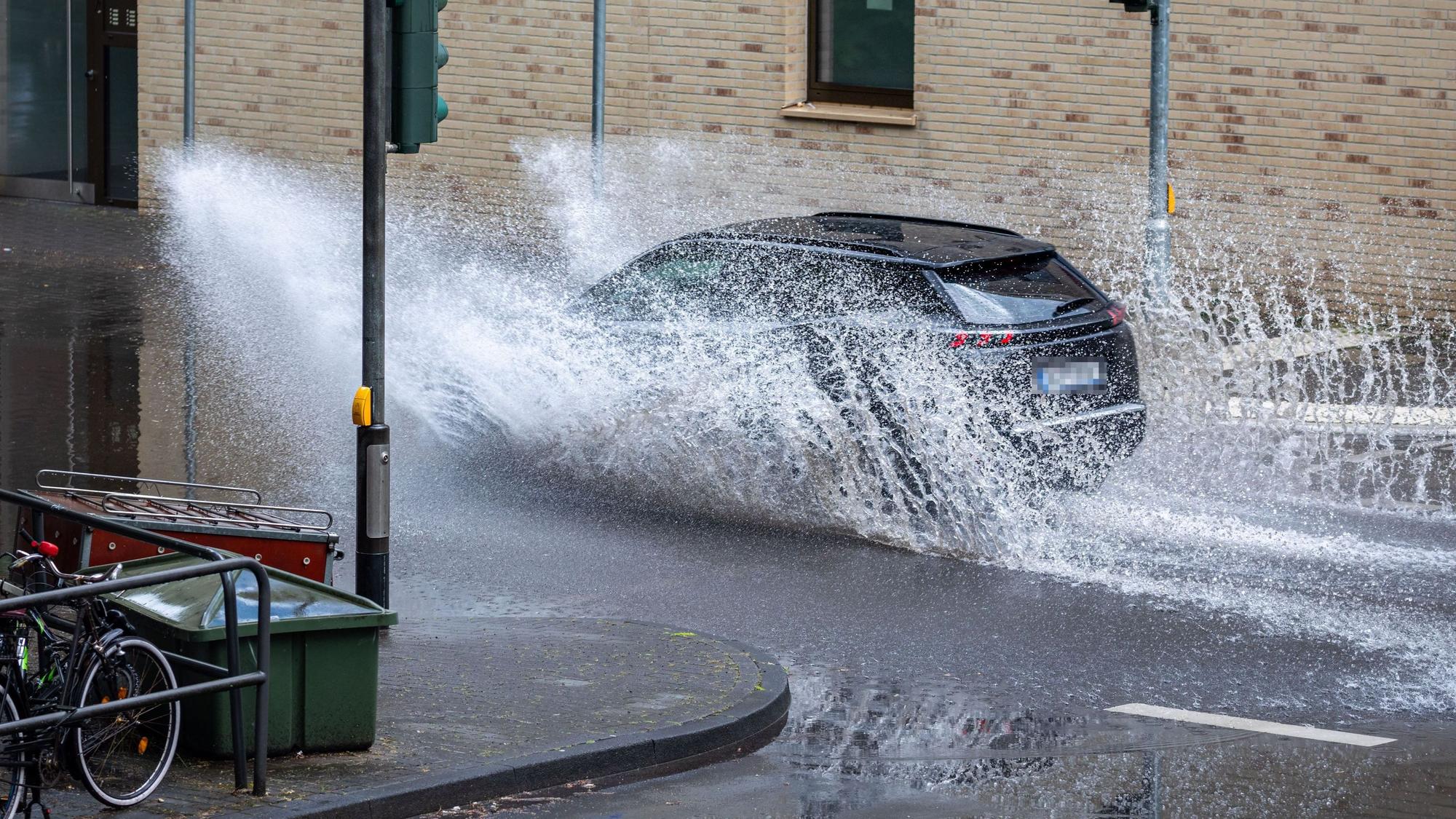 Ein Auto fährt durch eine Pfütze am Sülzgürtel.