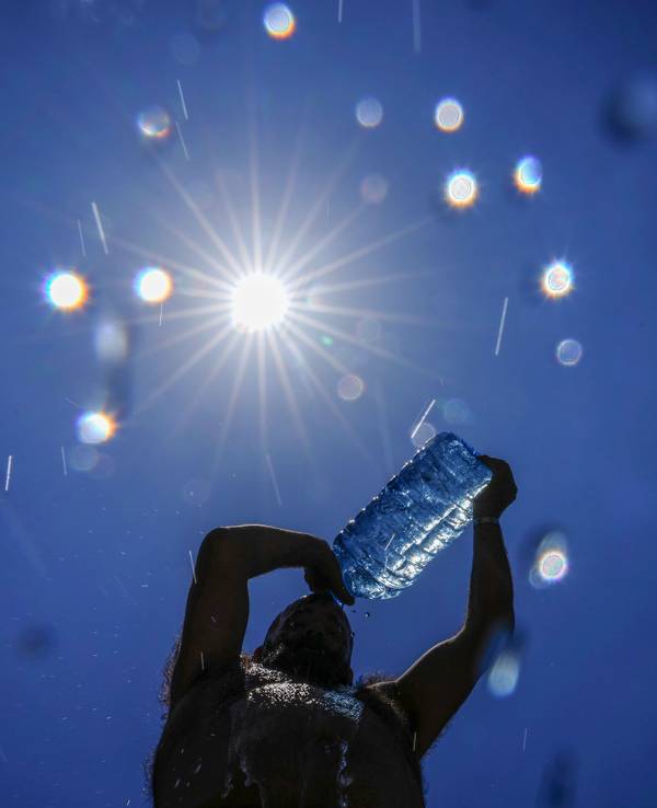 Ein Mann gießt sich Wasser über den Kopf, um sich abzukühlen.