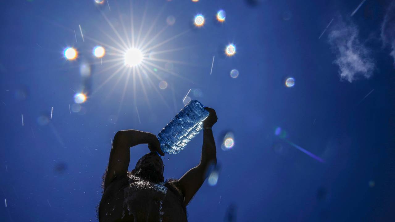 Ein Mann gießt sich Wasser über den Kopf, um sich abzukühlen.