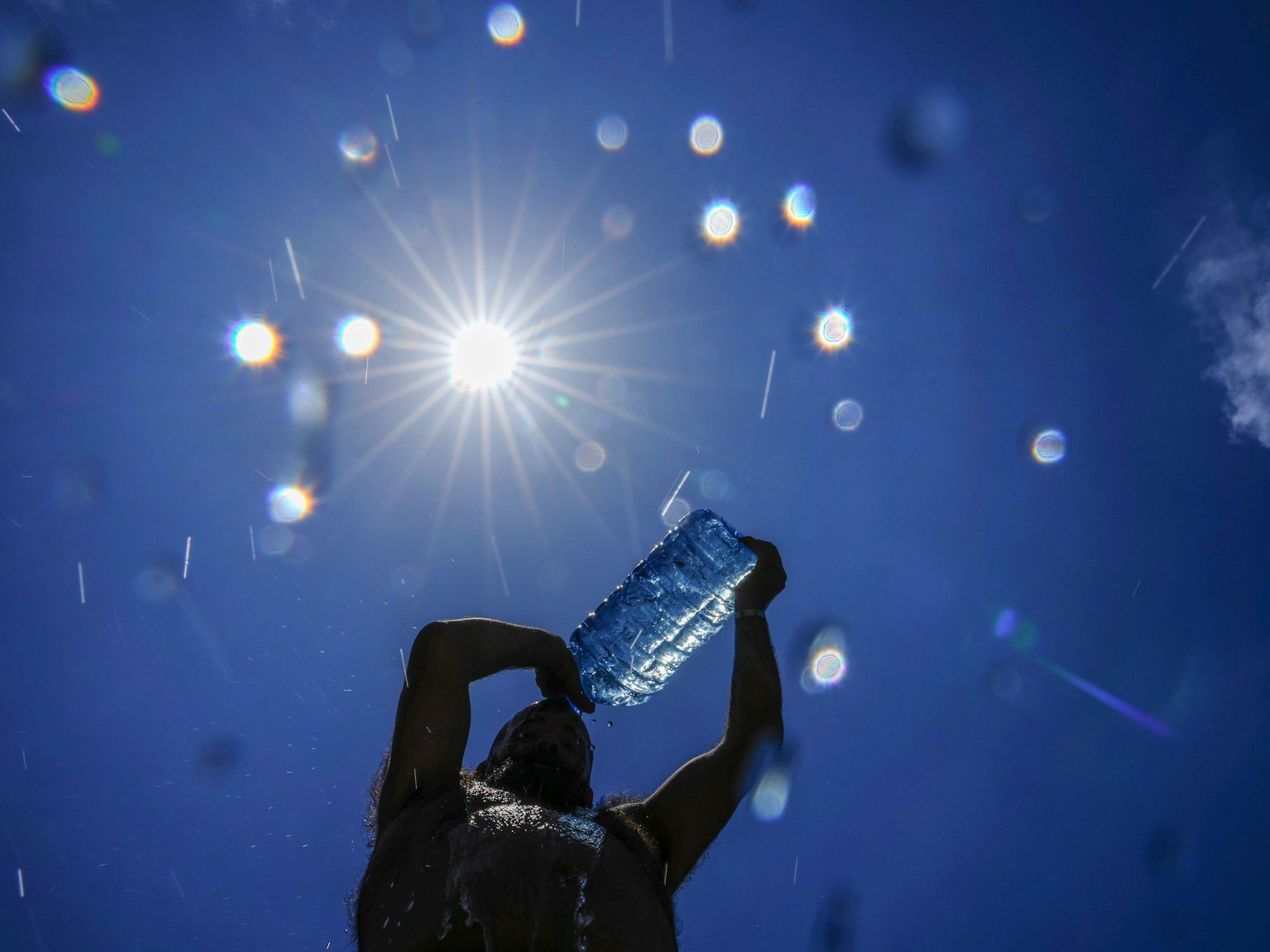 Ein Mann gießt sich Wasser über den Kopf, um sich abzukühlen.