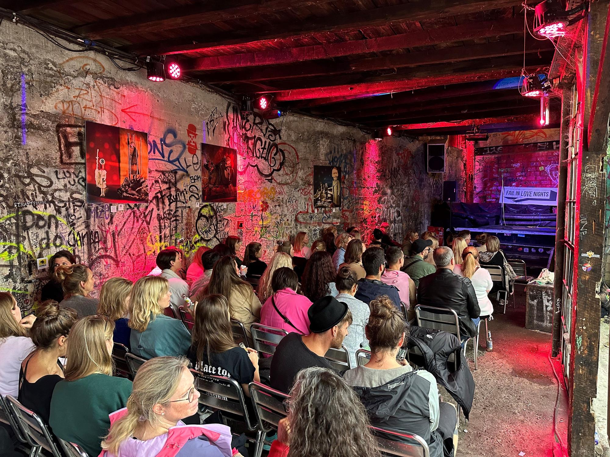 Das Publikum sitzt im Wintergarten des Odonien und schaut Richtung Bühne.