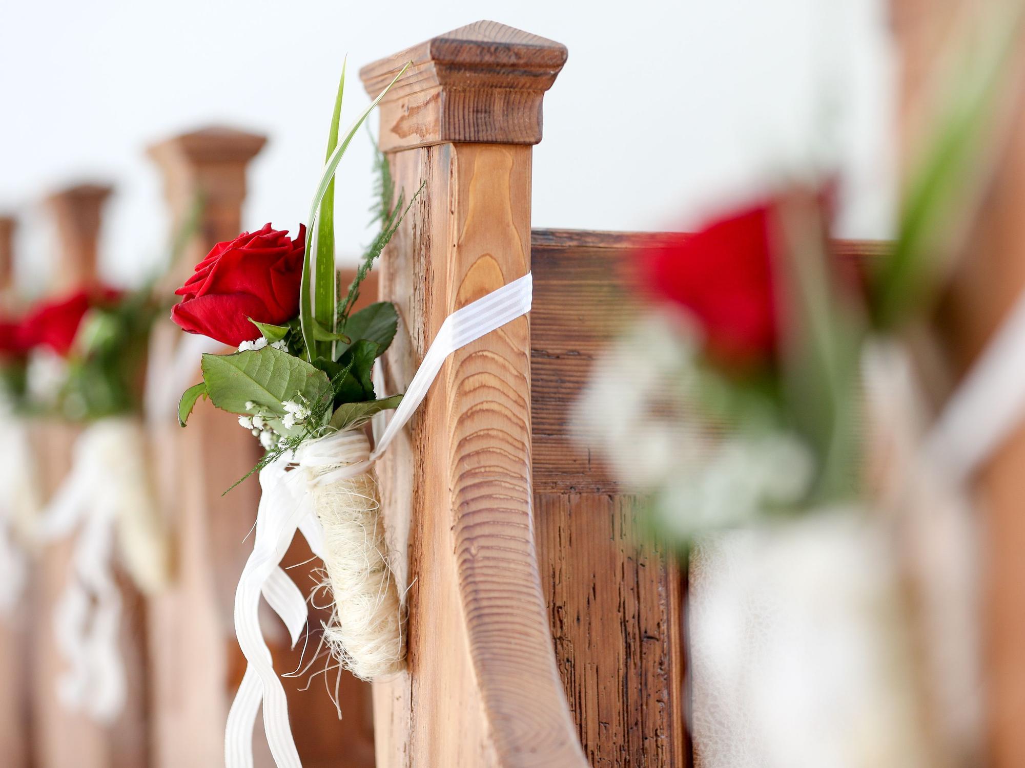 Blumen als Hochzeitsschmuck hängen an Kirchenbänken in einer Hochzeitskapelle, hier im September 2017 in Sachsen.