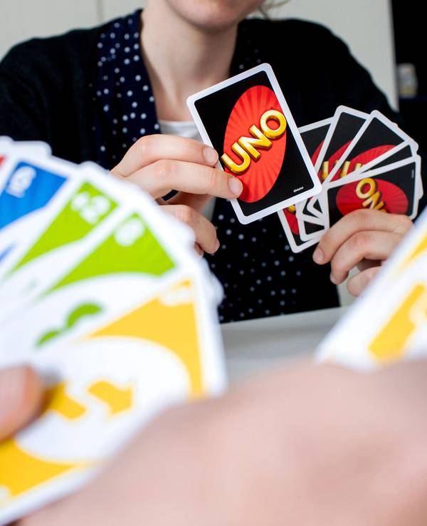 Eine Frau hält während einer Spielrunde die bunten Spielkarten des Kartenspiels „Uno“ in den Händen.