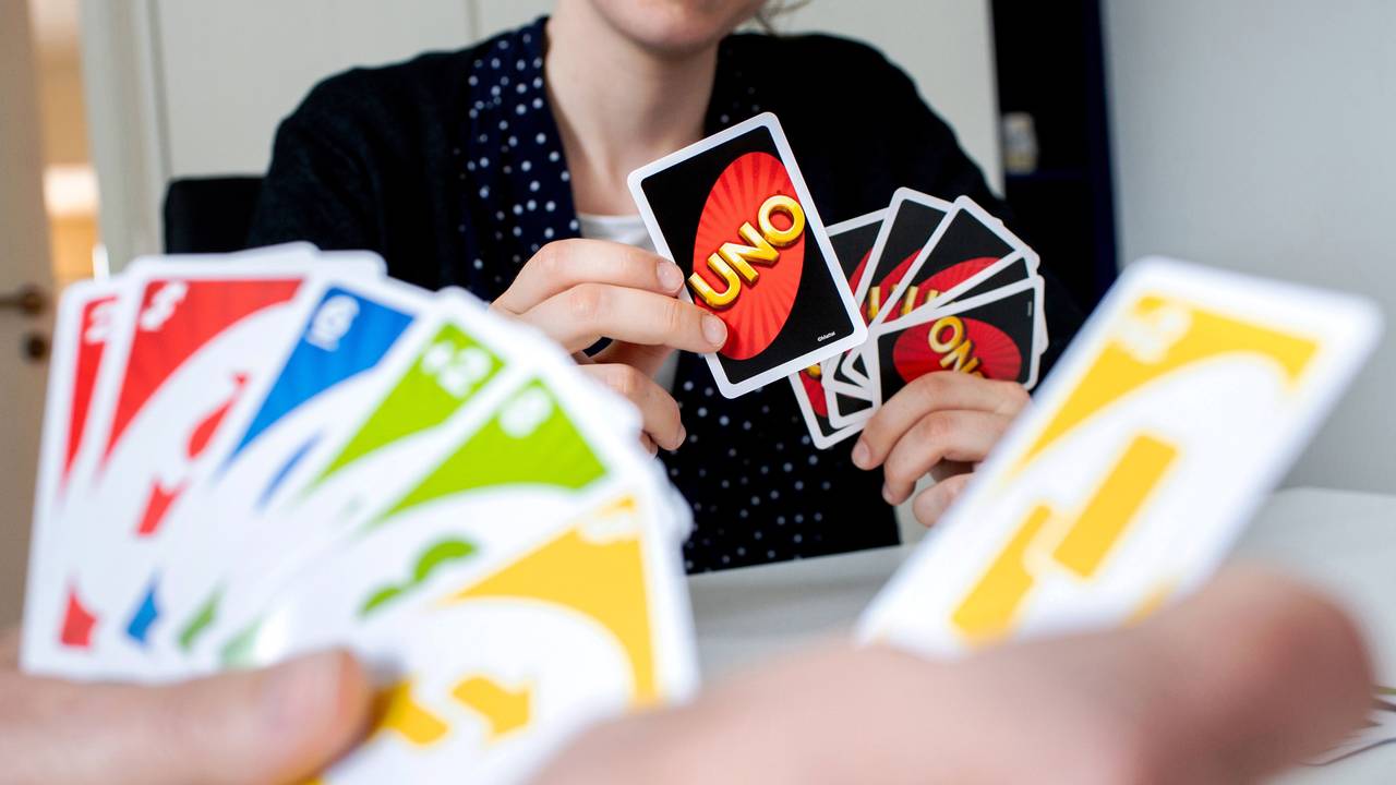 Eine Frau hält während einer Spielrunde die bunten Spielkarten des Kartenspiels „Uno“ in den Händen.
