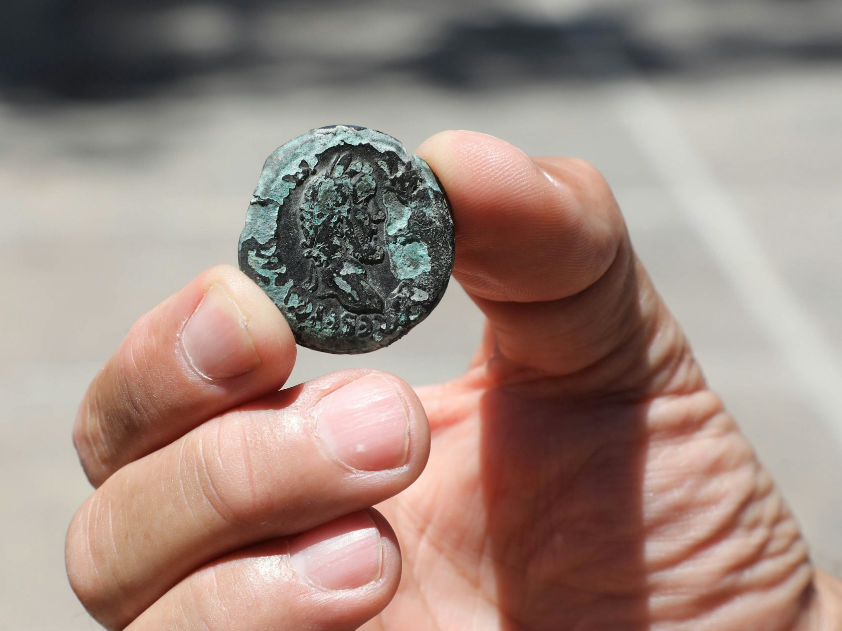 Ein Mann zeigt eine 1850 Jahre alte Bronzemünze in Jerusalem, hier im Juli 2022.