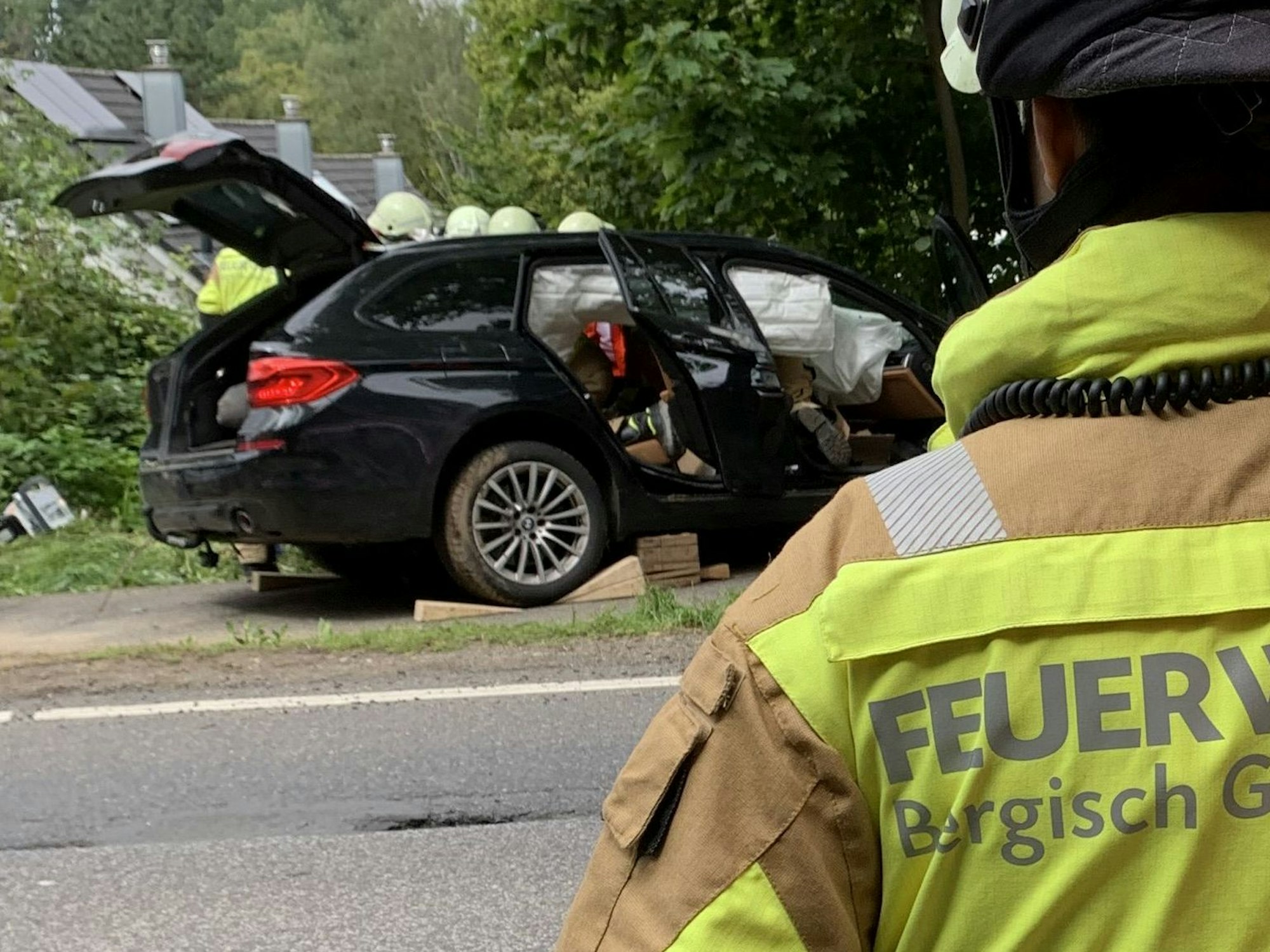 Die Feuerwehr Bergisch Gladbach am Unfallort in Moitzfeld. Einsatzkräfte durchsuchen den beschädigten BMW.