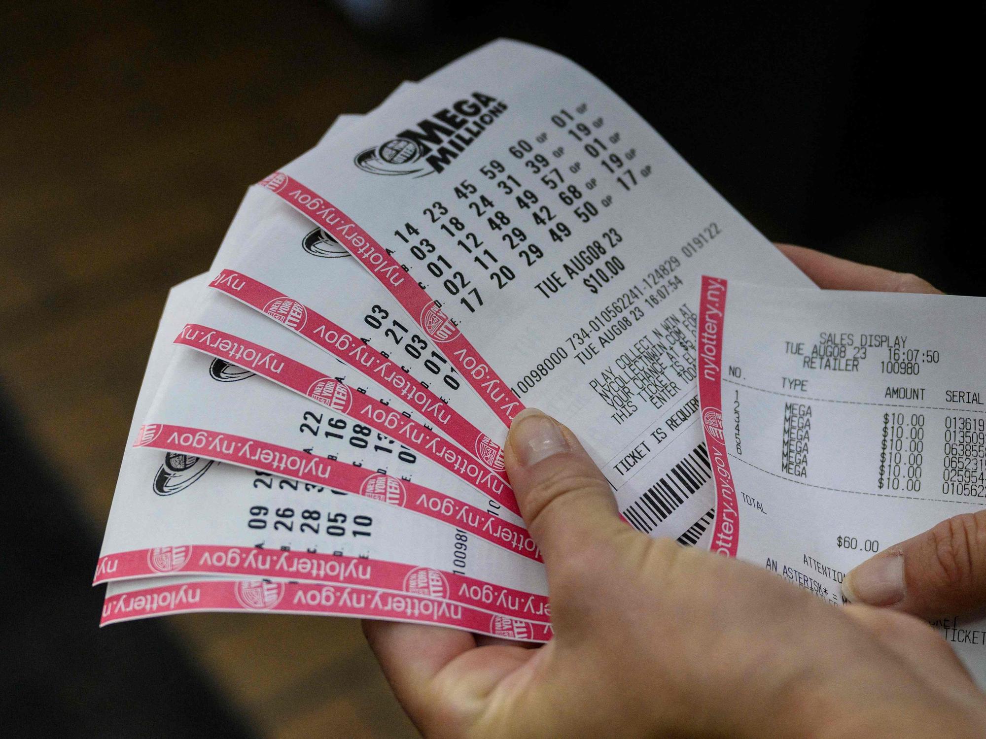 Eine Person hält ihre Mega-Millions-Spielscheine in der Hand.