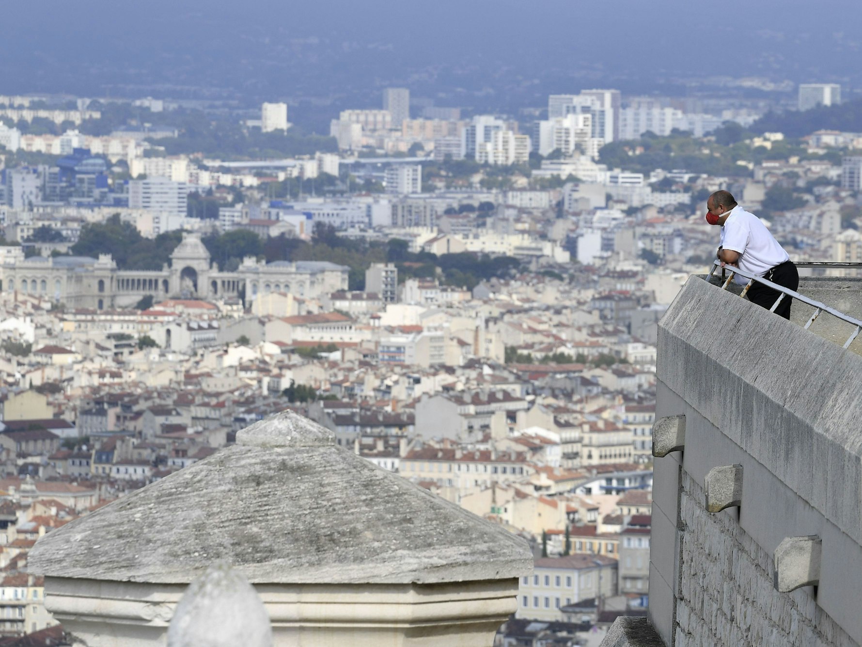 Ein Sicherheitspersonal, das eine schützende Gesichtsmaske trägt, genießt den Blick auf die Stadt von der Terrasse der Basilika Notre Dame de la Garde in Marseille, hier im Oktober 2020.