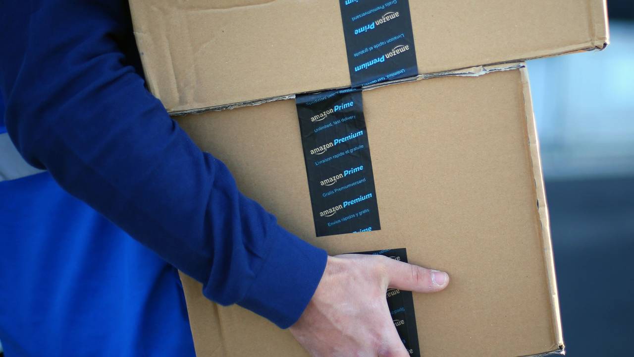 Ein Mitarbeiter trägt Pakete zu seinem Transportfahrzeug.