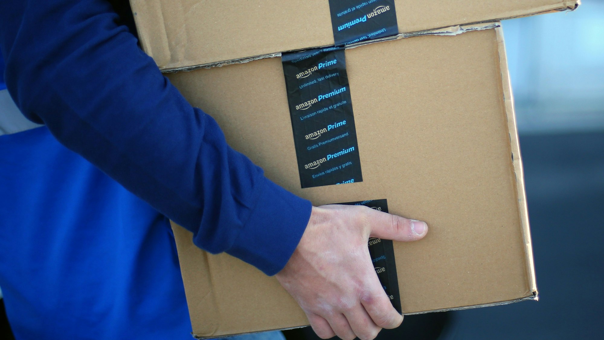 Ein Mitarbeiter trägt Pakete zu seinem Transportfahrzeug.