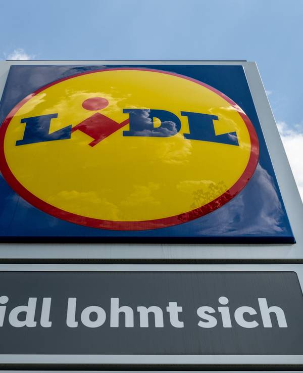 Eine Stele mit dem Logo des Discounters Lidl steht vor einer Filiale des Discounters.