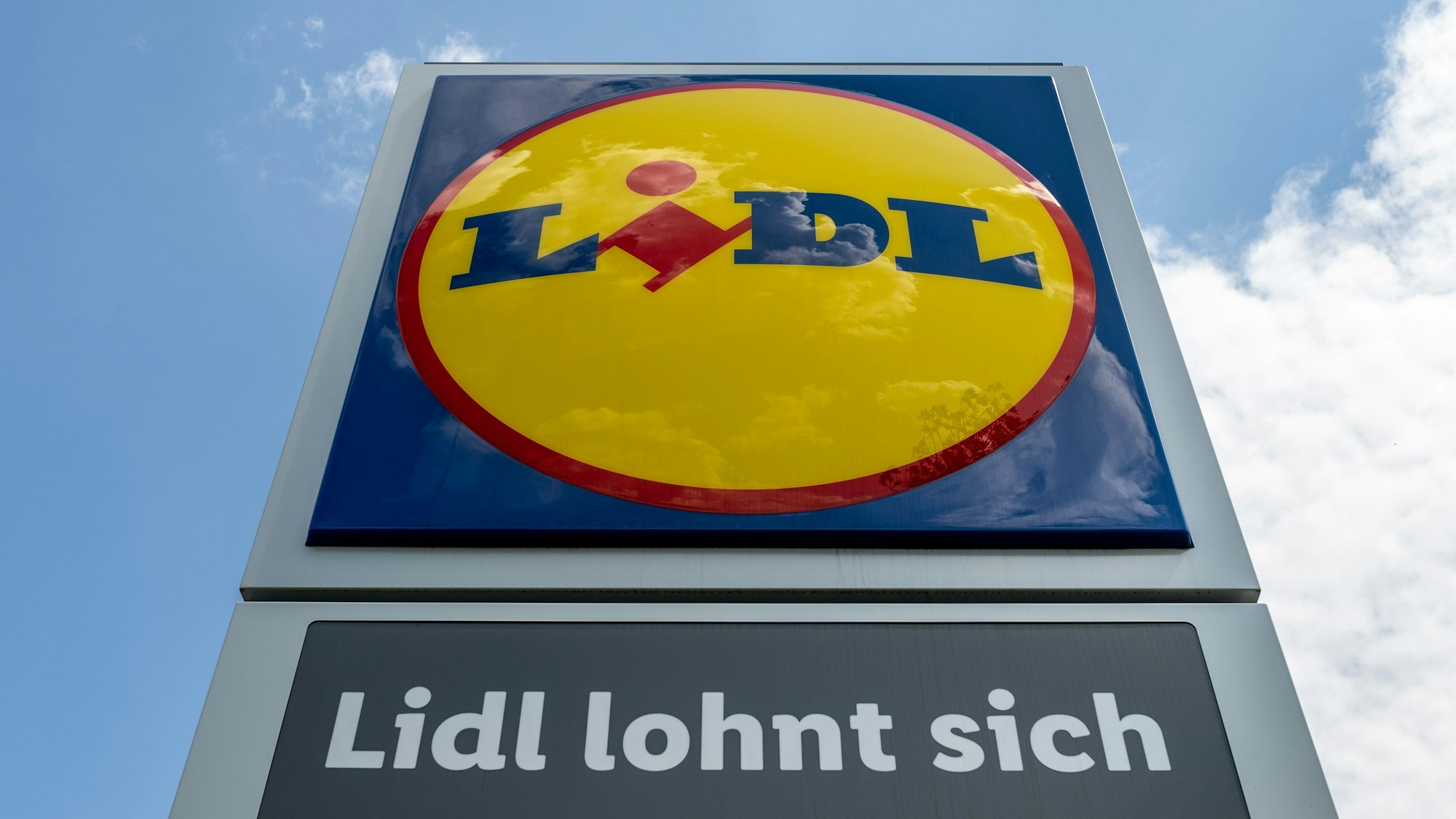 Eine Stele mit dem Logo des Discounters Lidl steht vor einer Filiale des Discounters.