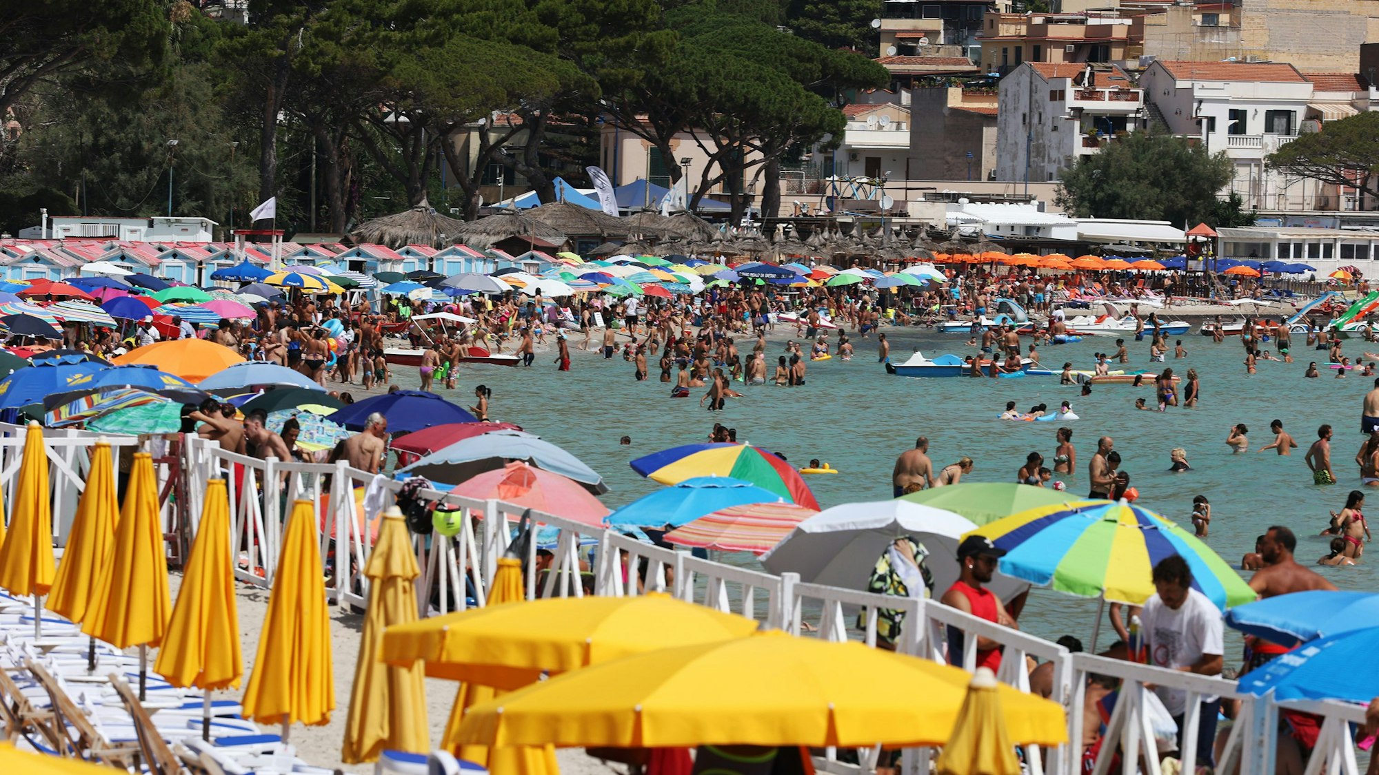 Zahlreiche Menschen liegen am Strand oder baden im Wasser.