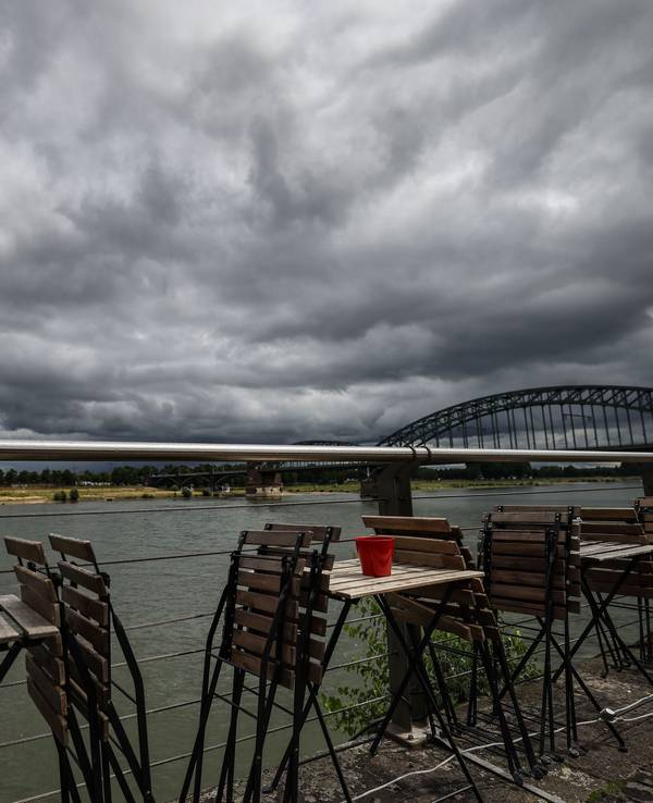 Stühle stehen Ende Juli vor einem Straßencafé am Rheinufer in Köln.