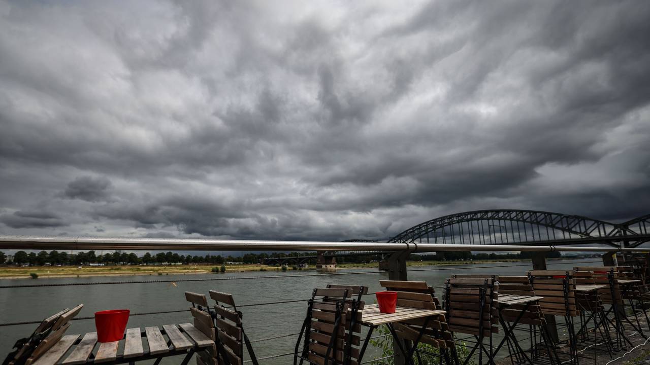 Stühle stehen Ende Juli vor einem Straßencafé am Rheinufer in Köln.