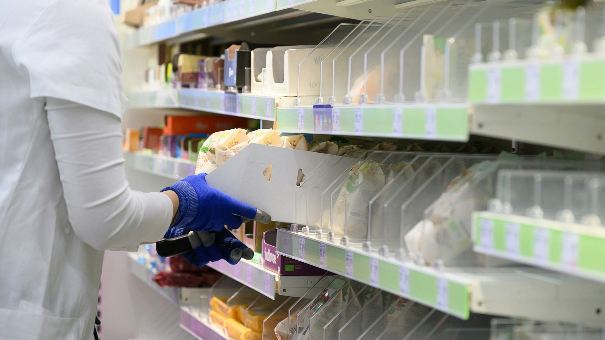 Eine Mitarbeiterin räumt in einem Drogeriemarkt der Kette dm-drogerie markt Nüsse in ein Regal.