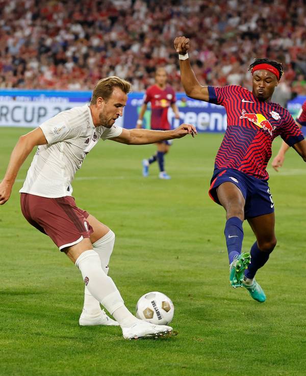 Bayerns Harry Kane (M) versucht sich gegen Leipzigs David Raum (l) und Leipzigs Mohamed Simakan durchzusetzen.