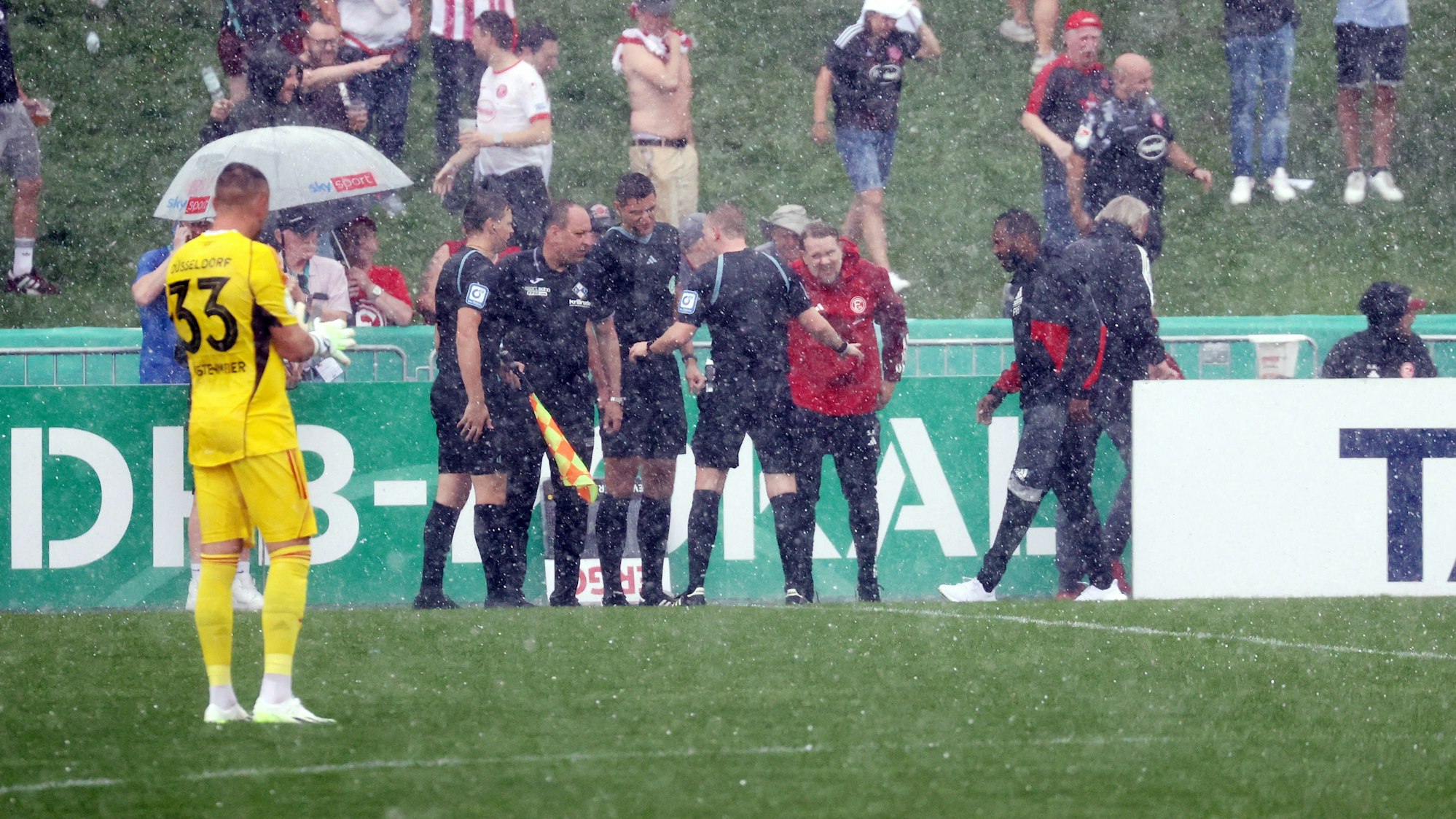 Es regnet sehr stark. Die Schiedsrichter beraten sich im strömenden Regen.