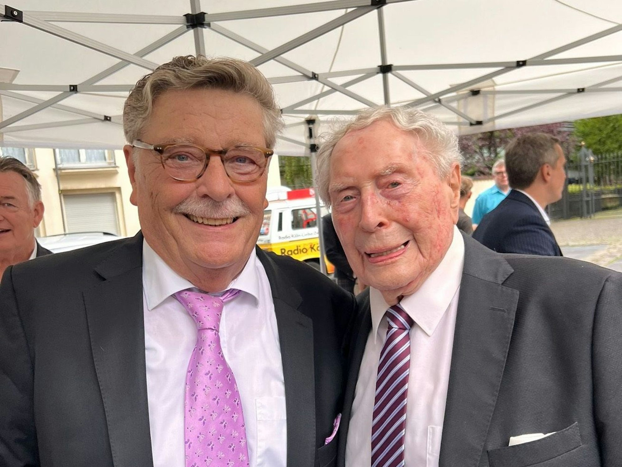 Fritz Schramma lächelt mit einem anderen Gast in die Kamera.