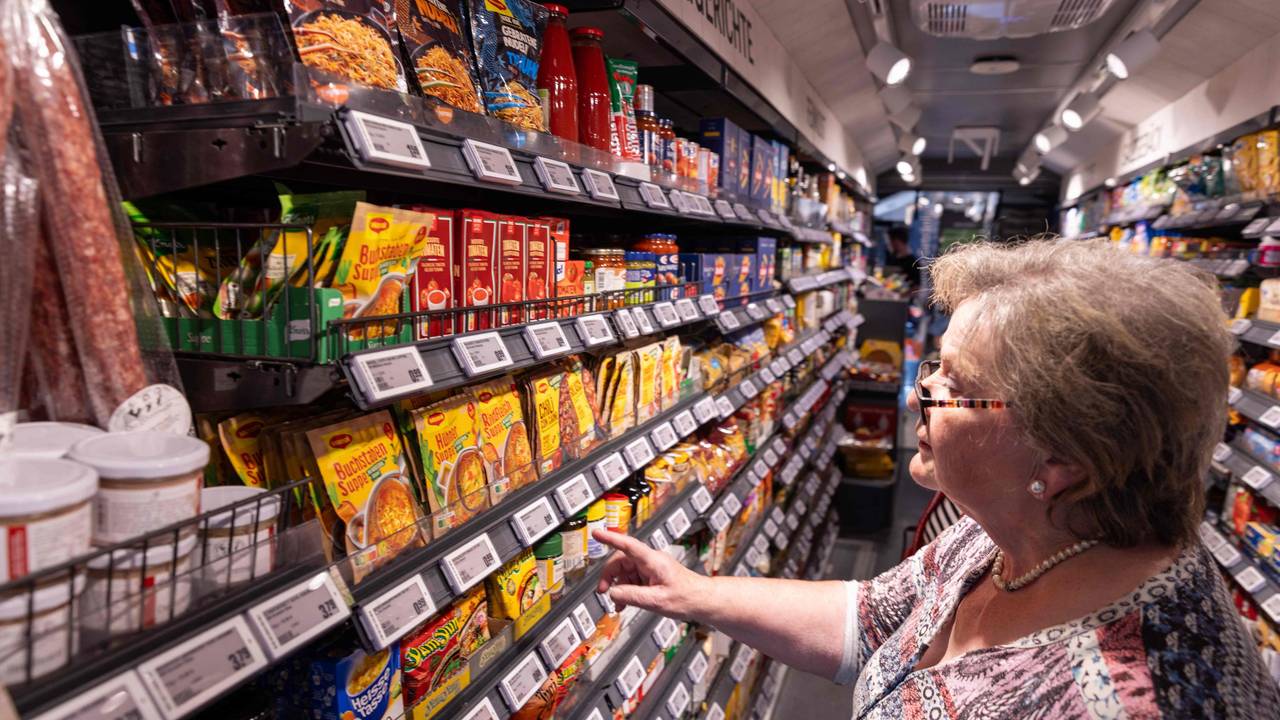 Eine Kundin greift in ein Regal bei Rewe.