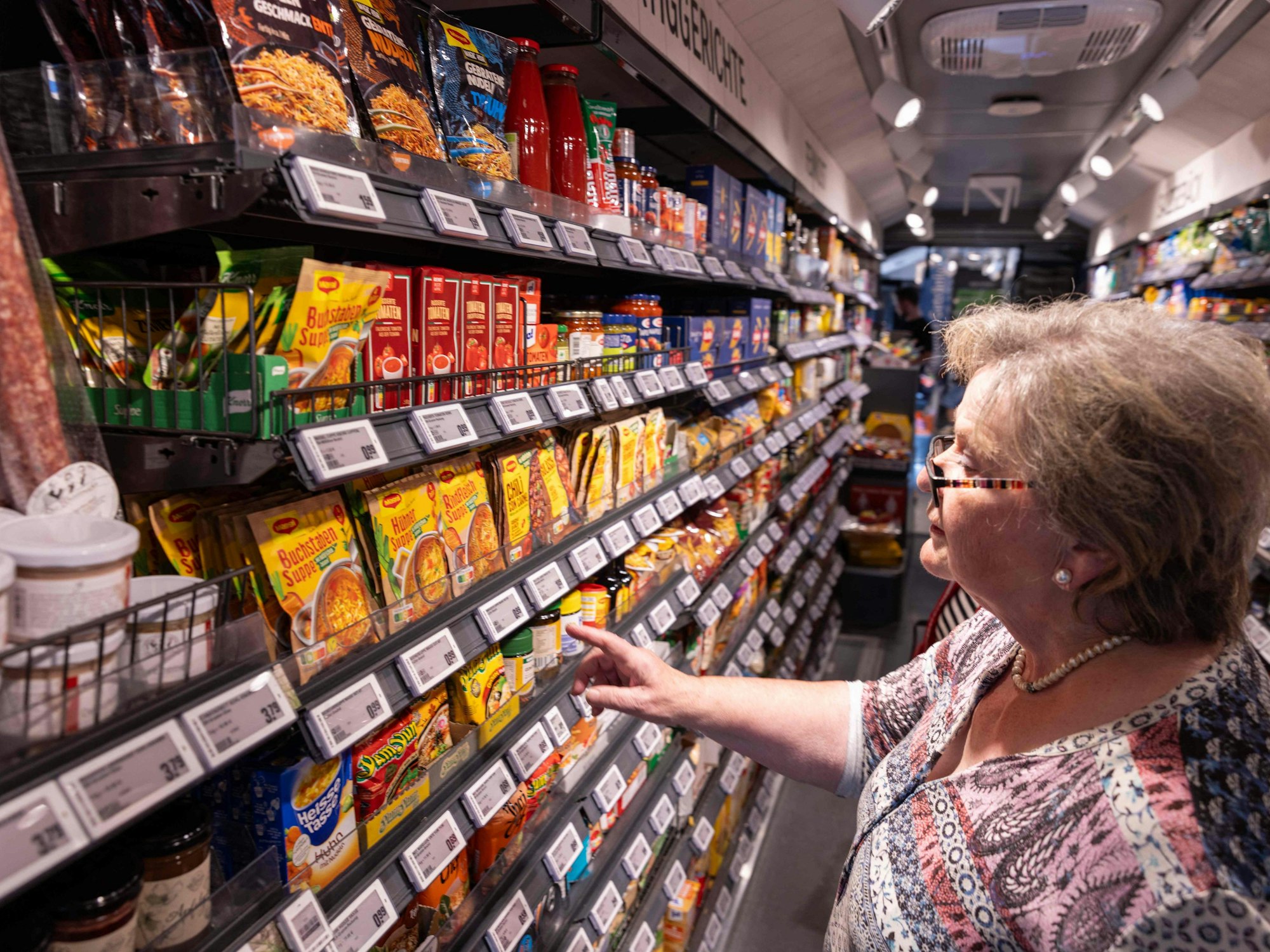 Eine Kundin greift in ein Regal bei Rewe.