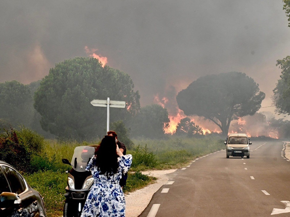 Eine Frau fotografiert in Saint-Andre in der Nähe von Argeles-sur-Mer im Südwesten Frankreichs einen Großbrand, der zur Evakuierung von rund 3000 Touristen von nahegelegenen Campingplätzen geführt hat.