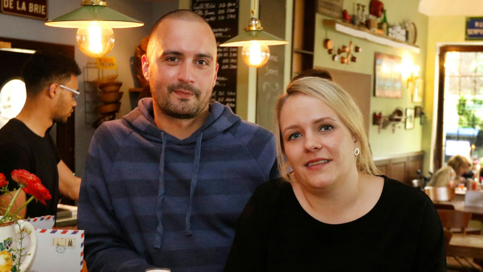 Ein Paar steht in einer Kneipe, vor sich ein Glas Kölsch.