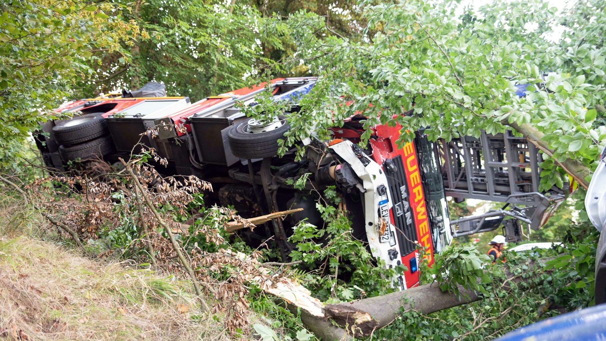 Ein Drehleiter-Fahrzeug der Feuerwehr ist in einer Böschung auf die Seite gekippt.