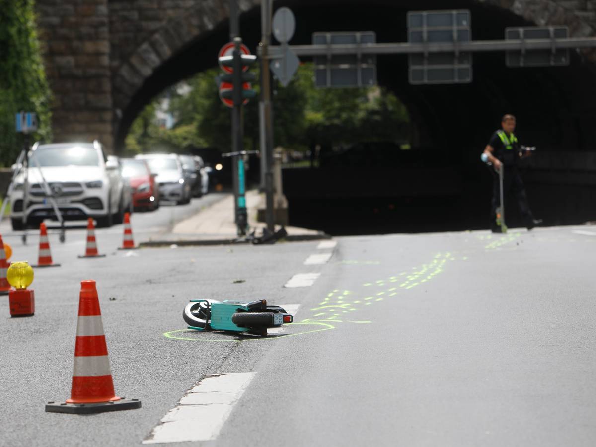 Ein kaputter E-Scooter liegt auf der Straße in Köln. Daneben sind Absperrungen der Polizei zu sehen.