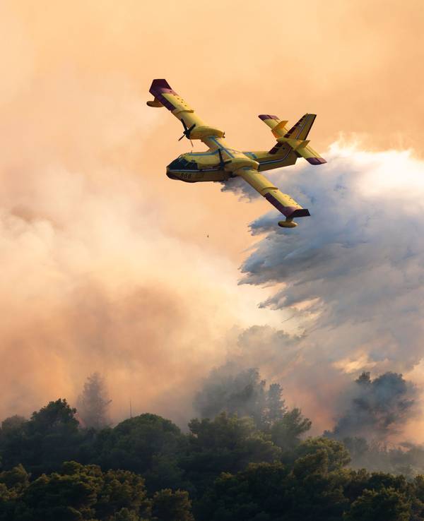 Ein Löschflugzeug versprüht Wasser, um einen Waldbrand auf der Insel Ciovo zu löschen.
