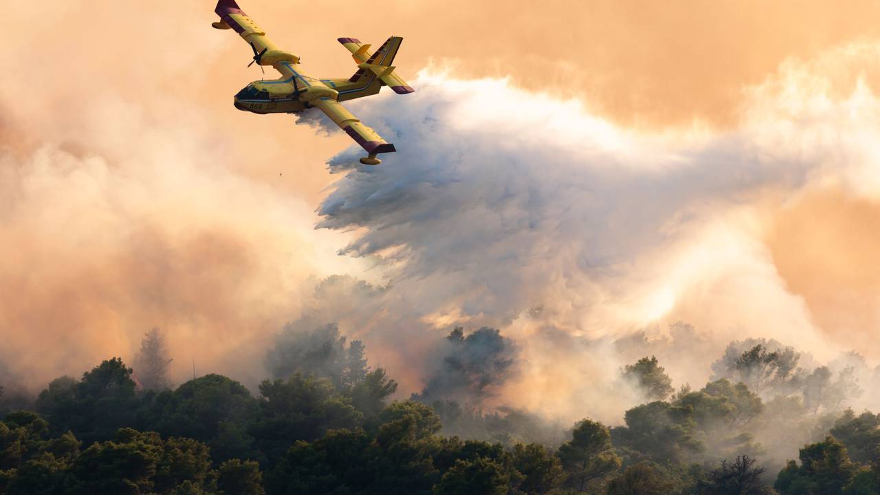 Ein Löschflugzeug versprüht Wasser, um einen Waldbrand auf der Insel Ciovo zu löschen.
