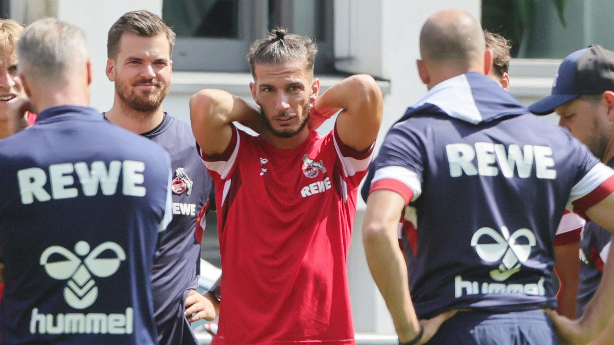 Leart Pacarada schlägt bei einer Teambesprechung auf dem Trainingsplatz die Arme hinter dem Kopf zusammen.