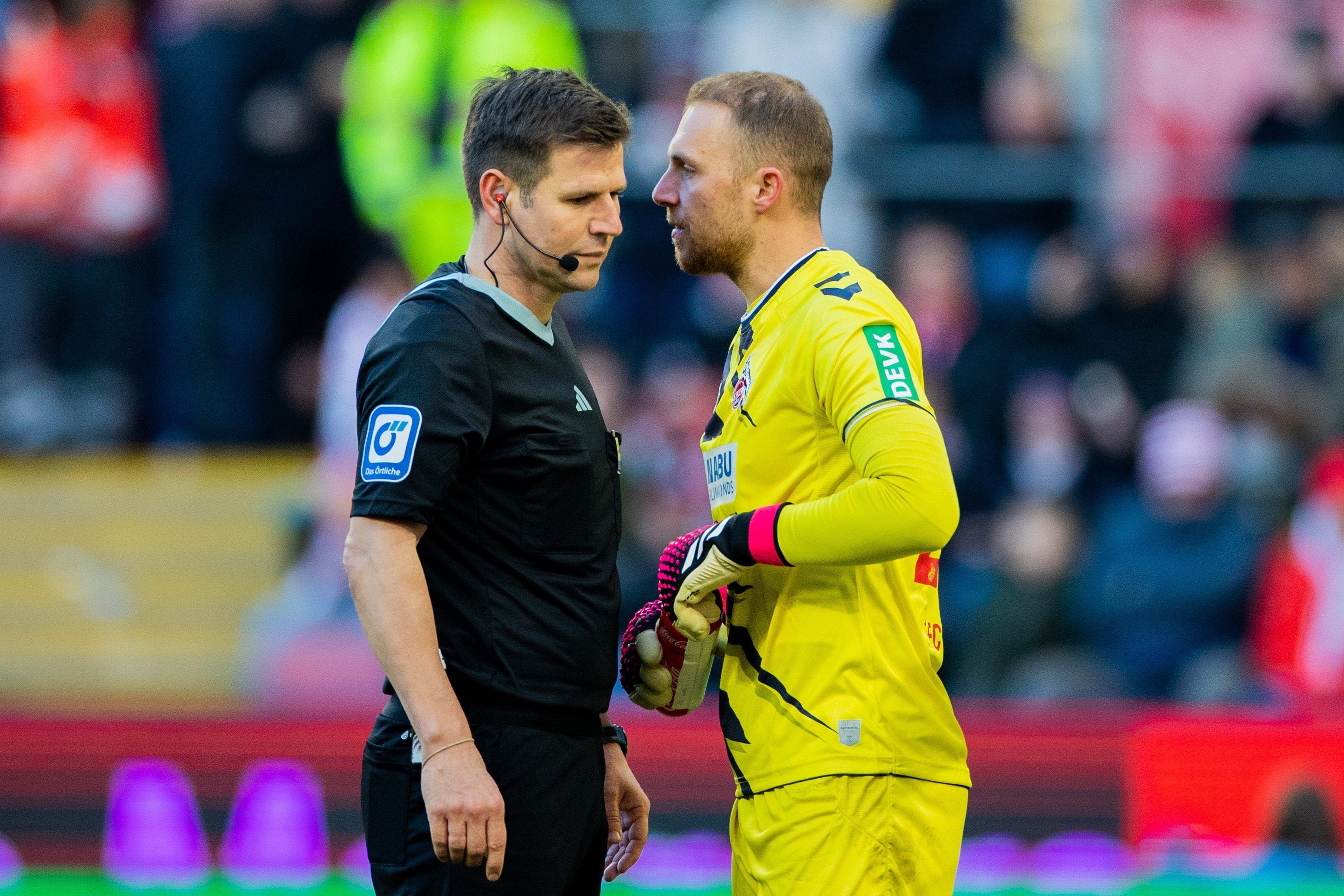 Kölns Torwart Marvin Schwäbe spricht auf dem Platz mit Schiedsrichter Frank Willenborg.