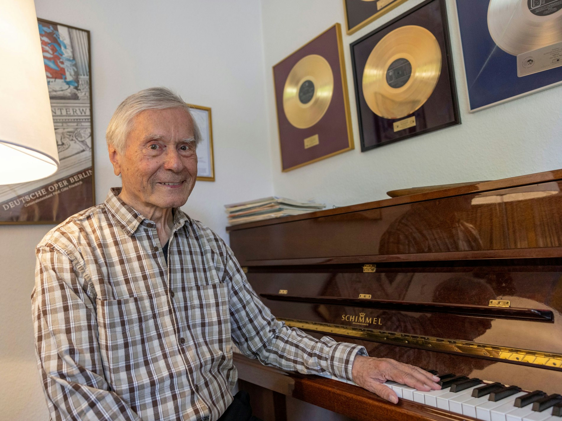Thomas Woitkewitsch sitzt an seinem Klavier, im Hintergrund sind goldene Schallplatten zu sehen.