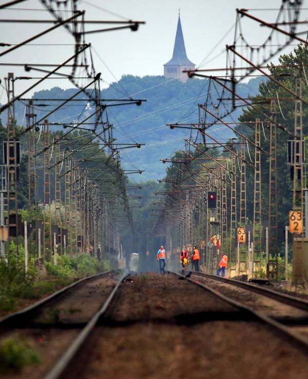 Bahn-Mitarbeitende laufen am 28. Juli 2014 unterhalb des Eltenberges über die Bahngleise.