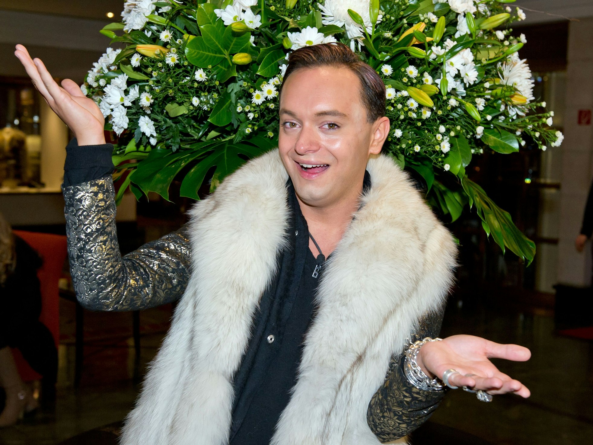 Julian F.M. Stoeckel posiert mit einem großen weißen Schal und dunklem Outfit für die Kamera.