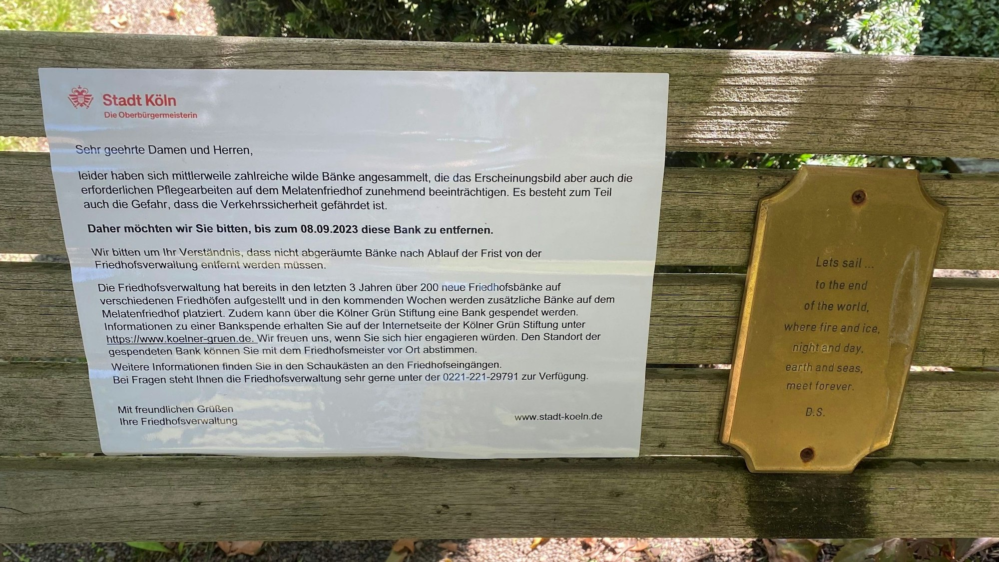 Ein Zettel der Stadt Köln klebt auf einer Bank.