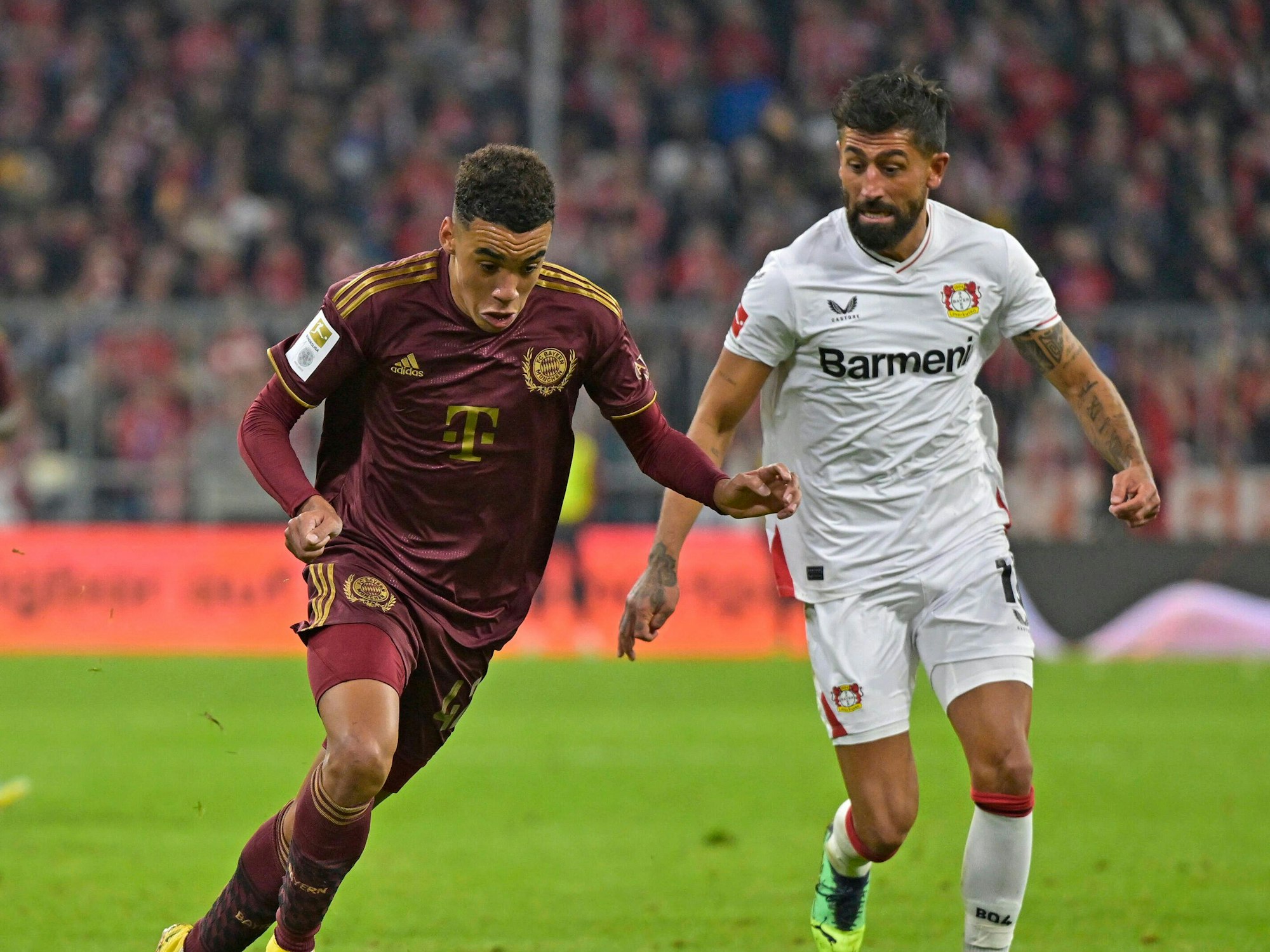 Bayerns Jamal Musiala hat den Ball, Leverkusens Kerem Demirbay vefolgt ihn.