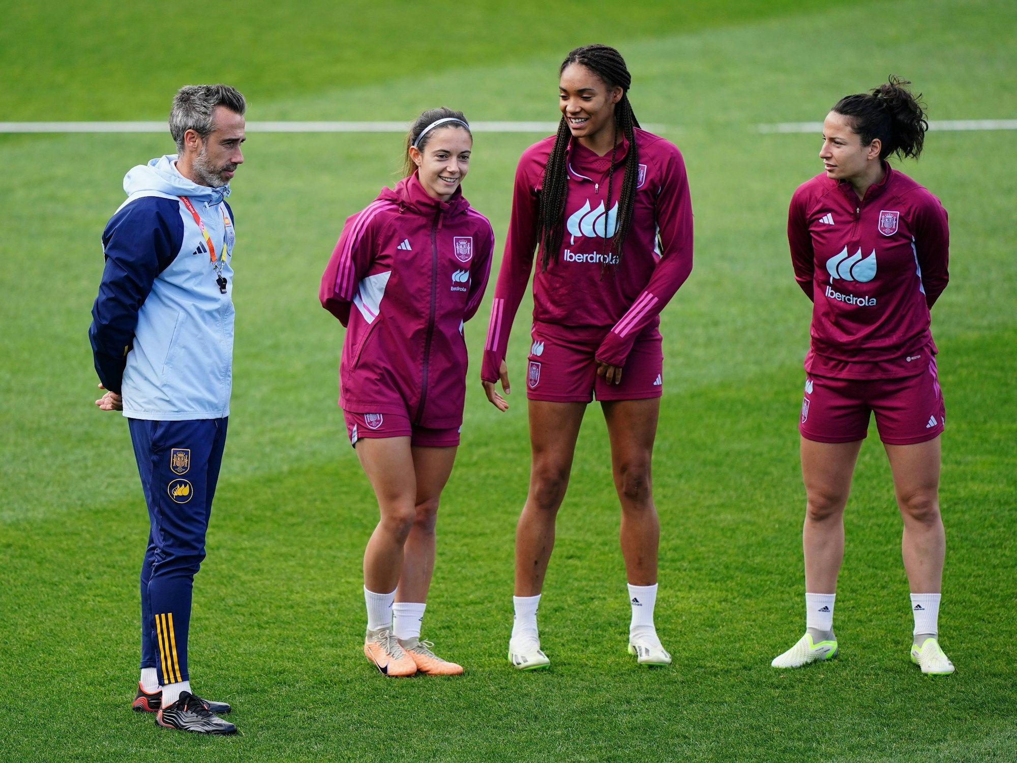 Trainer Jorge Vilda steht neben drei Nationalspielerinnen Spaniens auf dem Trainingsplatz.