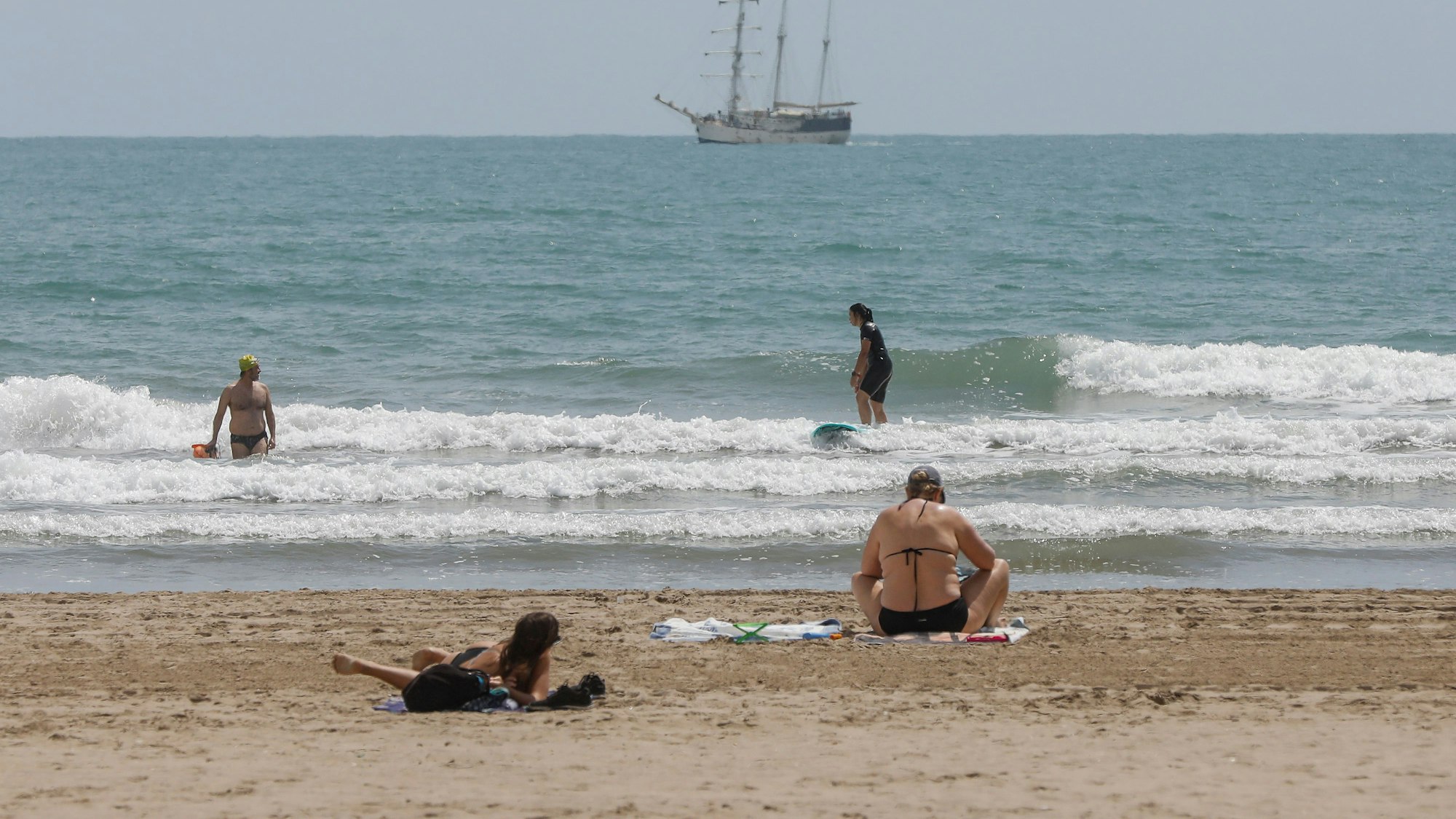 Mehrere Personen baden und sonnen sich an einem Strand in Valencia.