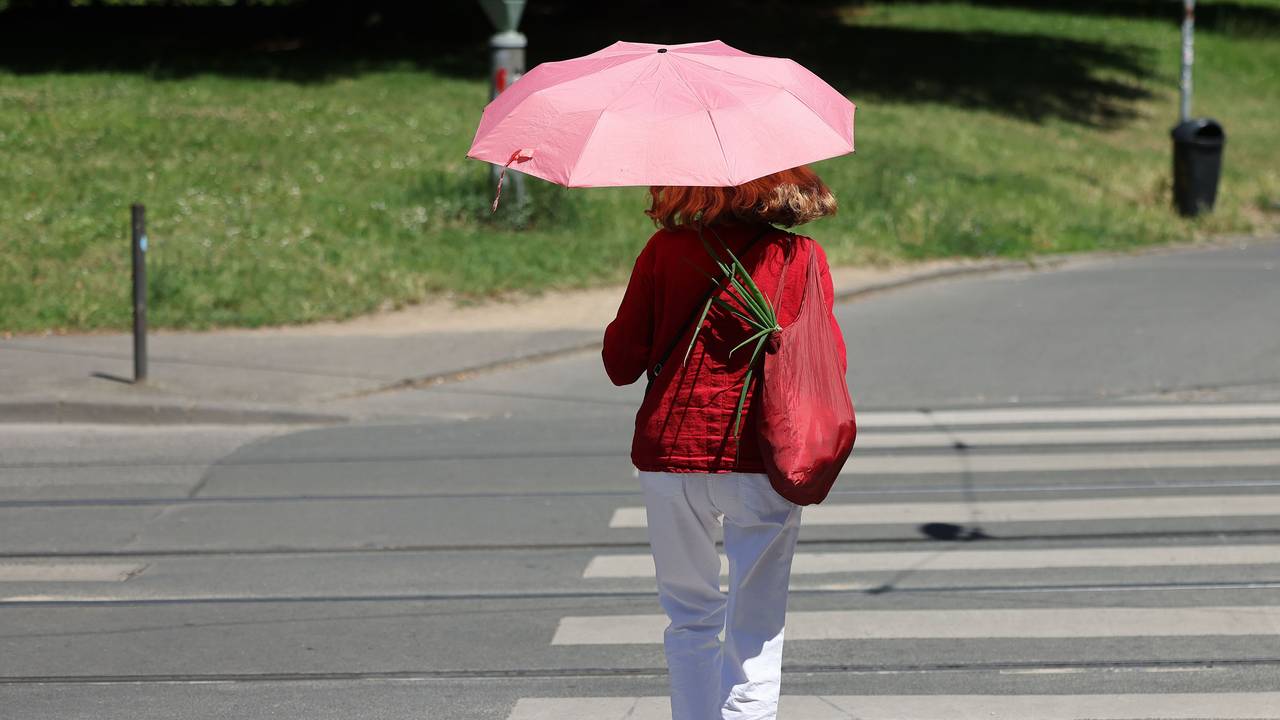 Eine Frau geht mit einem Regenschirm als Sonnenschirm durch Bonn: In Teilen von NRW warnt der Wetterdienst am Samstag vor Hitze.
