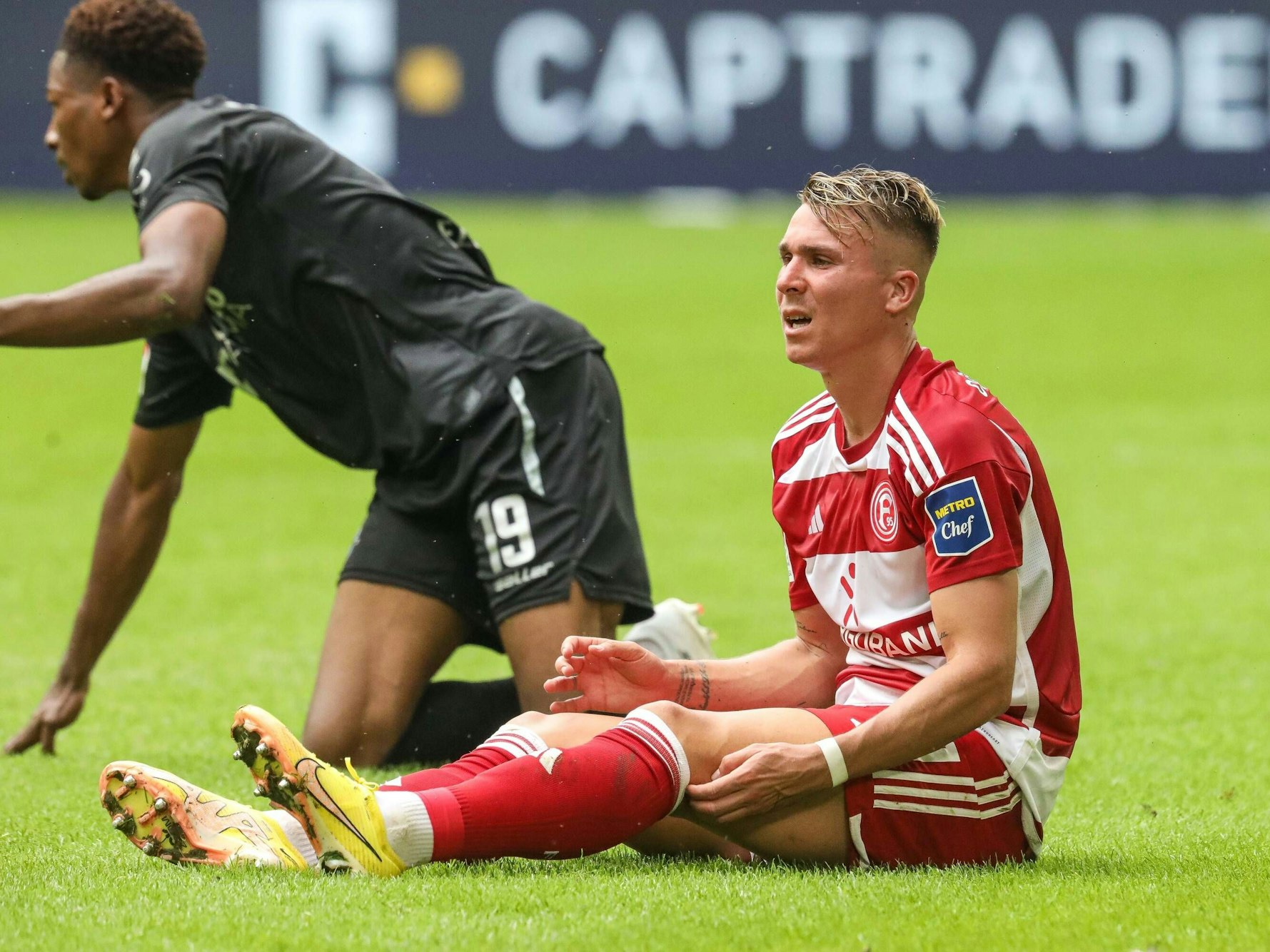Felix Klaus sitzt im Spiel gegen den SC Paderborn auf dem Rasen.