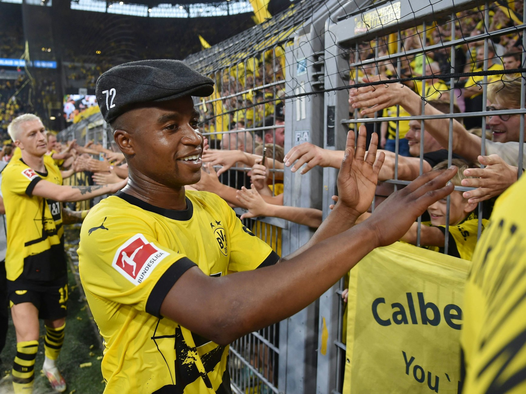 Youssoufa Moukoko klatscht nach dem Spiel mit der Mütze von Trainer Steffen Baumgart mit den Fans ab.