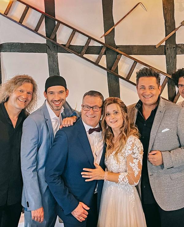 Ein Brautpaar steht mit fünf anderen Männer für ein Foto zusammen.