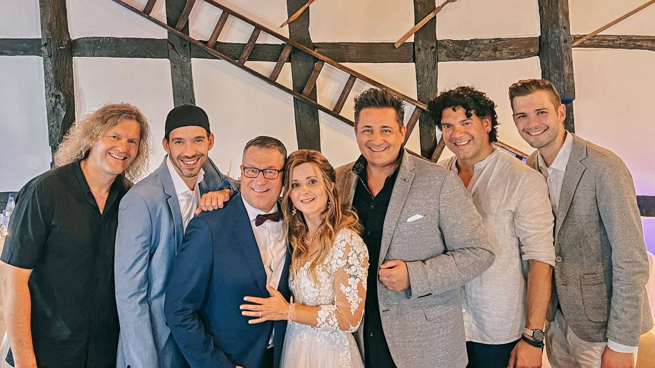 Ein Brautpaar steht mit fünf anderen Männer für ein Foto zusammen.