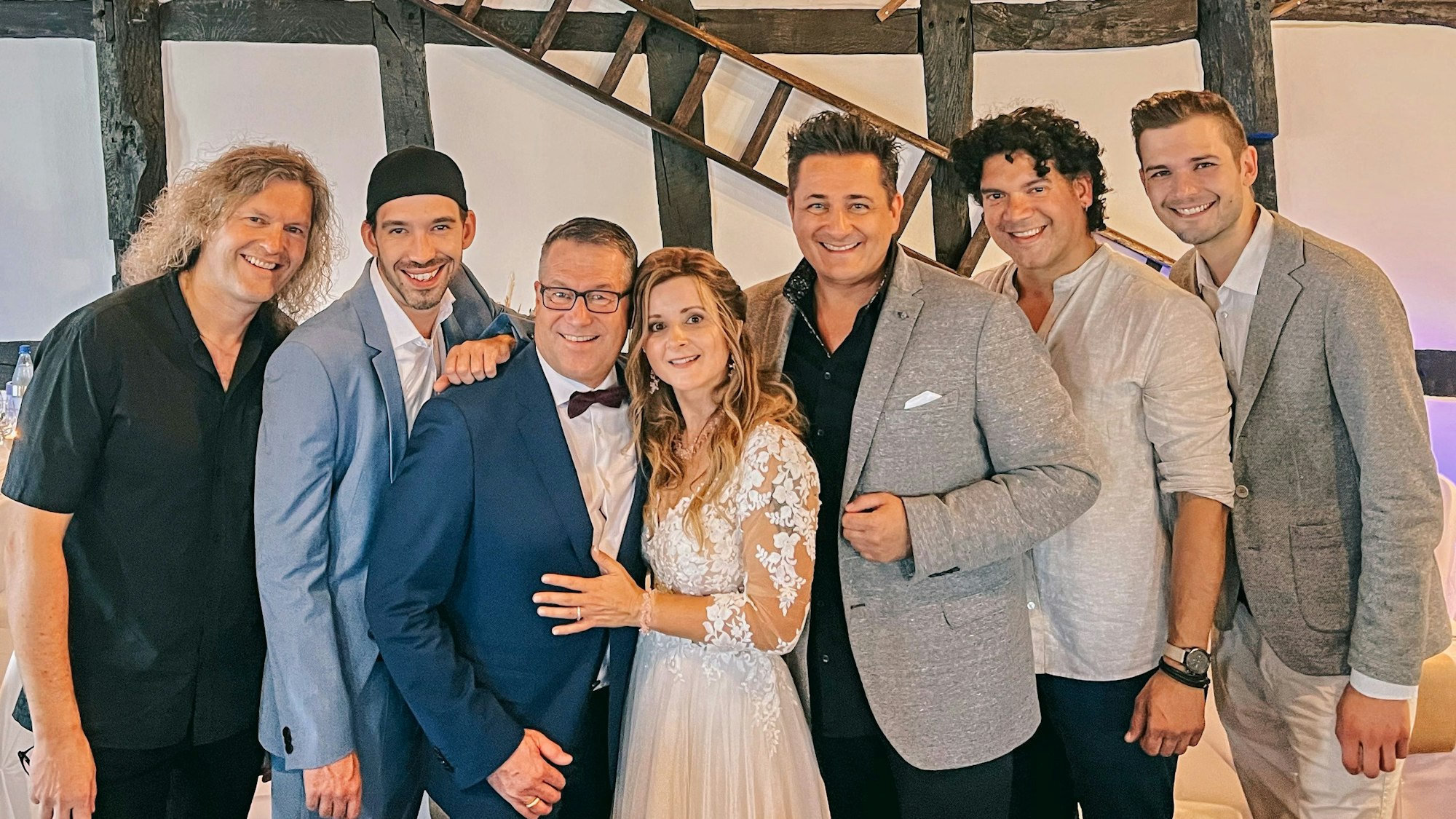 Ein Brautpaar steht mit fünf anderen Männer für ein Foto zusammen.